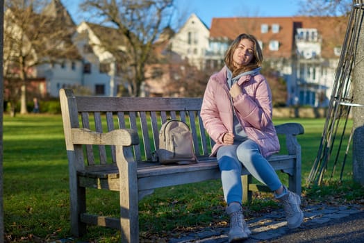 Experience the festive spirit of winter with this delightful image capturing a beautiful girl in a pink winter jacket sitting on a bench in a park, set against the backdrop of the historic town of Bitigheim-Bissingen, Baden-Württemberg, Germany. The scene features charming half-timbered houses, creating a picturesque blend of seasonal beauty and architectural charm. Winter Wonderland Elegance: Beautiful Girl in Pink Jacket Enjoys Festive Atmosphere in Bitigheim-Bissingen Park. Experience the magic of the holiday season as a charming girl in a pink winter jacket sits on a bench in a park against the backdrop of the historic town of Bitigheim-Bissingen, Baden-Württemberg, Germany. The scene is adorned with picturesque half-timbered houses, creating a delightful blend of winter charm and architectural beauty.