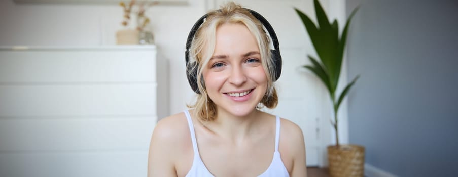 Concept of people and lifestyle, Close up of beautiful blond woman in wireless headphones, listens to music, enjoys good quality sound in new earphones.