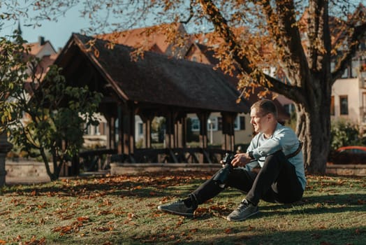 Professional photographer taking picture of beautiful autumn park. man professional photographer sit with camera in autumn park