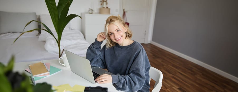 Portrait of young woman, lifestyle blogger, recording vlog video about her life and daily routine, sitting in front of laptop, talking to followers, sitting in her room.