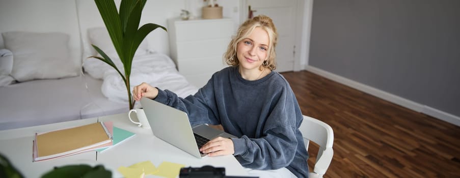 Portrait of young woman, lifestyle blogger, recording vlog video about her life and daily routine, sitting in front of laptop, talking to followers, sitting in her room.