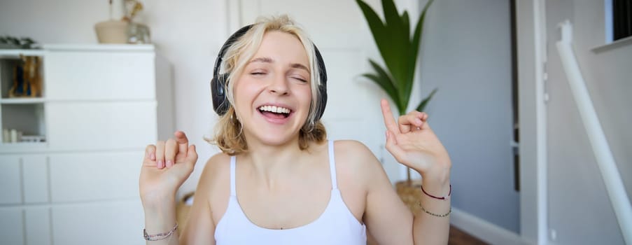 Dancing girl listens to music, woman wears wireless headphones and enjoys sound quality, sings.