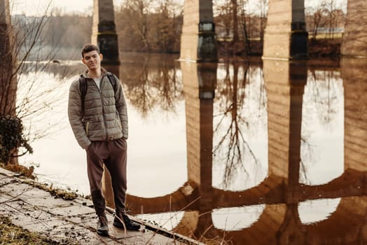 Youthful Exploration: 17-Year-Old Teen in Stylish Jacket by Neckar River and Historic Bridge in Bietigheim-Bissingen, Germany. Capture the essence of seasonal charm as a 17-year-old teenager stands confidently by the picturesque Neckar River, adorned in a fashionable jacket, against the backdrop of the historic bridge pillars in the city of Bietigheim-Bissingen, Germany. This captivating image blends youthful style with cultural heritage, offering a glimpse into the unique blend of modern fashion and historical architecture, creating an enchanting scene of urban exploration during the autumn or winter season.