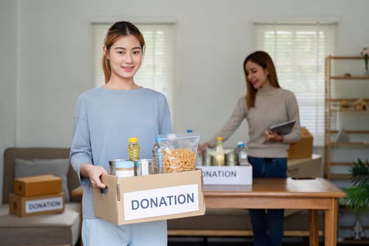 charity, donation and volunteering concept. Volunteer prepare foodstuff box containing food to donate to people poor, disaster victim at home.