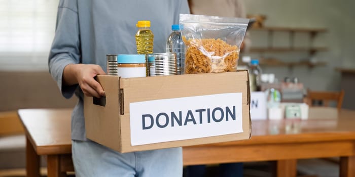 charity, donation and volunteering concept. Volunteer prepare foodstuff box containing food to donate to people poor, disaster victim at home.