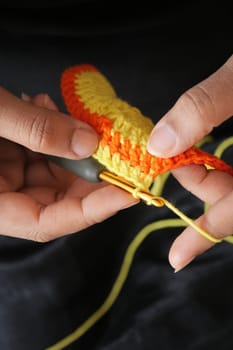 Hand close up crocheting with a hook, wool yarn, creative craft.