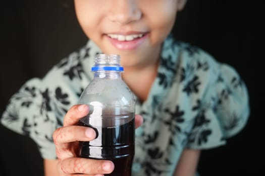 a little girl holding a bottle of soft drinks .