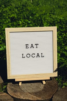 EAT LOCAL message on background of fresh eco-friendly bio grown green herb parsley in garden. Countryside food production concept. Locally produce harvesting. Sustainability and responsibility