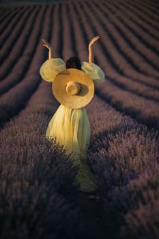 Woman lavender field sunset. Back view woman in yellow dress and hat. Aromatherapy concept, lavender oil, photo session in lavender.