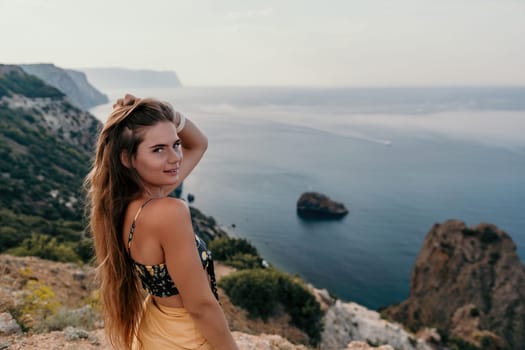 Woman travel sea. Happy tourist taking picture outdoors for memories. Woman traveler looks at the edge of the cliff on the sea bay of mountains, sharing travel adventure journey.