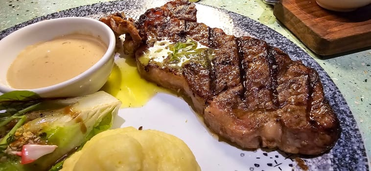 Beef New York strip loin steak or sirloin steak served with potatoes, and mushroom sauce and salad on plate Marble premium beef