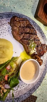 Beef New York strip loin steak or sirloin steak served with potatoes, and mushroom sauce and salad on plate Marble premium beef