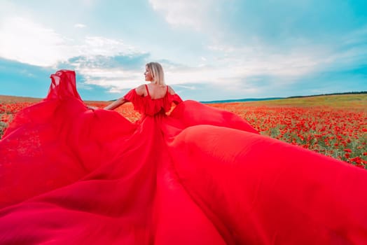 Woman poppy field red dress. Happy woman in a long red dress in a beautiful large poppy field. Blond stands with her back posing on a large field of red poppie