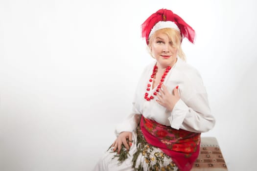 Portrait of cheerful funny adult mature woman solokha. Female model in clothes of national ethnic Slavic style. A stylized Ukrainian, Belarusian or Russian woman poses in a comic photo shoot