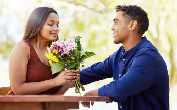 Man, woman and bouquet at restaurant, outdoor and happy with present, love and romance in summer. Couple, date and smell flowers for gift with smile, care and connection on holiday in countryside.