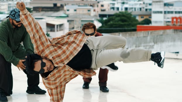 Professional hispanic break dancer practice B boy dance while multicultural friends at roof top with cityscape, urban. Young modern dancing group doing hip hop movement. Outdoor sport 2024. Endeavor.