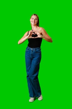 Young Woman Making Heart With Hands on green background in studio