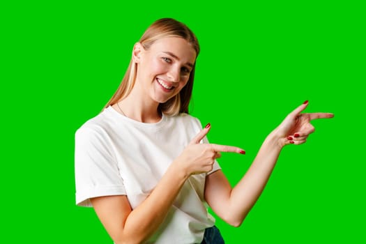Young Woman Pointing at Something against green background in studio
