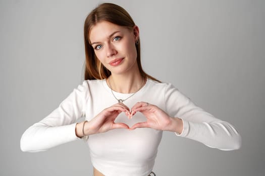 Young Woman Making Heart Shape With Hands in studio