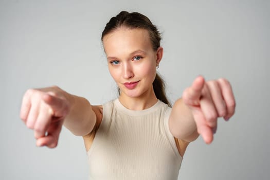 Young Woman in Tank Top Pointing at Camera in studio