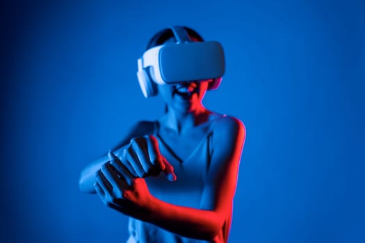 Smart female stand wear VR headset connecting metaverse, future cyberspace community technology. Elegant woman using hands controlling virtual laser saber seriously play fighting games. Hallucination.