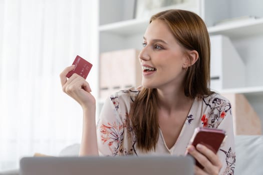 Young happy woman buy product by online shopping at home while ordering items from the internet with credit card online payment system protected by utmost cyber security from online store platform