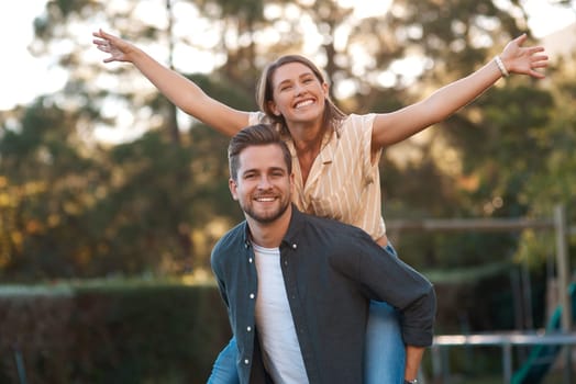 Man, woman and portrait with piggyback outdoor for relationship connection, anniversary or celebration. Happy couple, face and romance date in garden with airplane game for fun, playing or bonding.