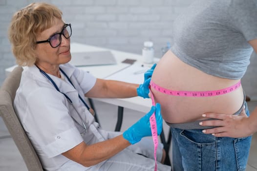 Doctor measuring the volume of a pregnant woman's abdomen using a tape in inches