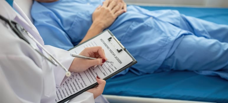 A female doctor is examining the body and taking notes on a sick person in a hospital examination room..