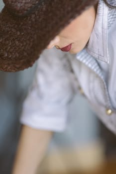 Indoor portrait of a young beautiful fashionable woman wearing stylish accessories. Hidden eyes with hat. Female fashion, beauty and advertisement concept. Close up. Copy space for text.