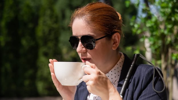 Blind woman in business suit drinking coffee in outdoor cafe