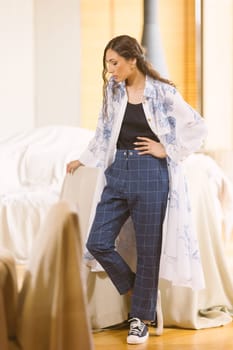 Fashionable confident woman wearing elegant suit, trousers posing in interior. Studio fashion portrait.