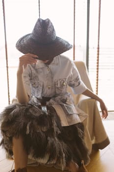 Indoor portrait of a young beautiful fashionable woman wearing stylish accessories. Hidden eyes with hat. Female fashion, beauty and advertisement concept. Close up. Copy space for text.