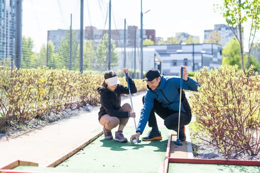 young handsome father teaching his little daughter how to play golf. High quality photo