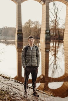 Youthful Exploration: 17-Year-Old Teen in Stylish Jacket by Neckar River and Historic Bridge in Bietigheim-Bissingen, Germany. Capture the essence of seasonal charm as a 17-year-old teenager stands confidently by the picturesque Neckar River, adorned in a fashionable jacket, against the backdrop of the historic bridge pillars in the city of Bietigheim-Bissingen, Germany. This captivating image blends youthful style with cultural heritage, offering a glimpse into the unique blend of modern fashion and historical architecture, creating an enchanting scene of urban exploration during the autumn or winter season.
