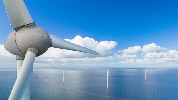 A single wind turbine stands tall in the middle of the vast ocean, harnessing renewable energy while surrounded by an endless expanse of water under a clear blue sky in the Noordoostpolder Netherlands