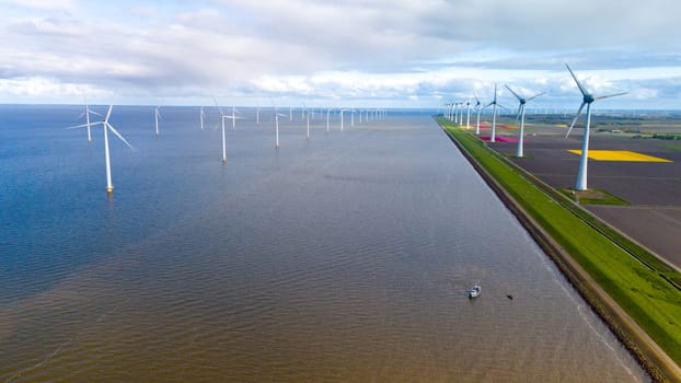 A serene body of water glistens under a clear sky, with a row of towering windmills lining the horizon in the Netherlands in Spring. windmill turbines in the ocean