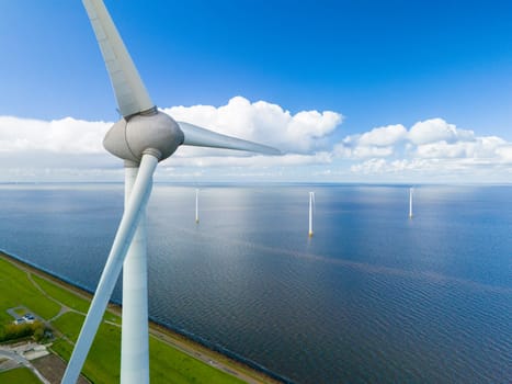A single wind turbine towers over the ocean, its blades spinning gracefully in the wind, harnessing the power of nature in the picturesque setting of the Netherlands in Spring.