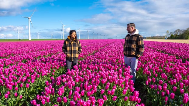 Two people stand amidst a vibrant sea of wildflowers in a Dutch field, embraced by the beauty of nature in full bloom. a couple of men and women in a tulip field in the Noordoostpolder Netherlands