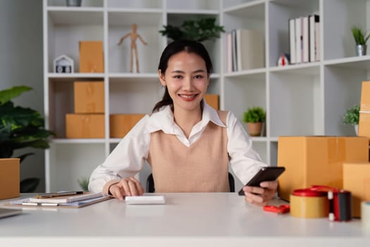 Young business woman asian working online ecommerce shopping at her shop. Young woman sell prepare parcel box of product for deliver to customer. Online selling.