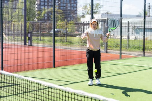 Young sporty woman performing basic strokes during paddle tennis group training. High quality photo