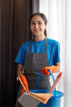 Cleaning product, and basket with woman asian staff cleaning service in bedroom to clean bacteria at apartment. cleaner or maid with container to work in room.