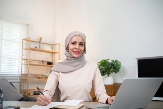 Young muslim business woman accountant working with financial document bills, calculate tax. Woman muslim freelancer paperwork at home.