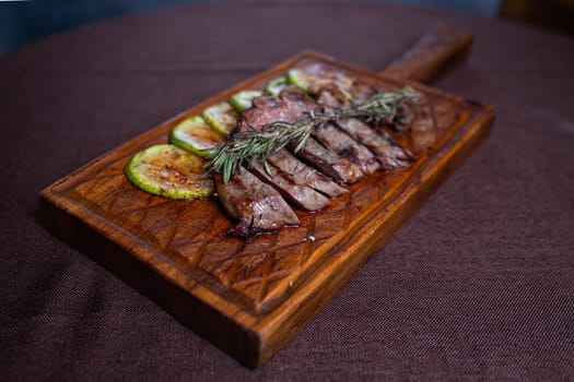 Tender beef steak with grilled zucchini on a wooden board, a delicious and healthy meal option for food enthusiasts.