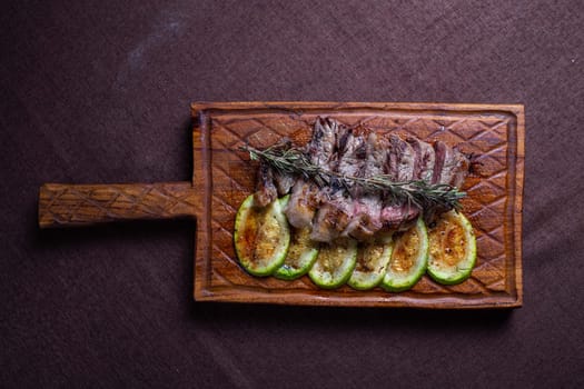 Tender beef steak with grilled zucchini on a wooden board, a delicious and healthy meal option for food enthusiasts.