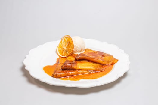 Indulge in a tempting dessert of crepes bathed in a zesty orange sauce and crowned with creamy ice cream for a delightful treat.