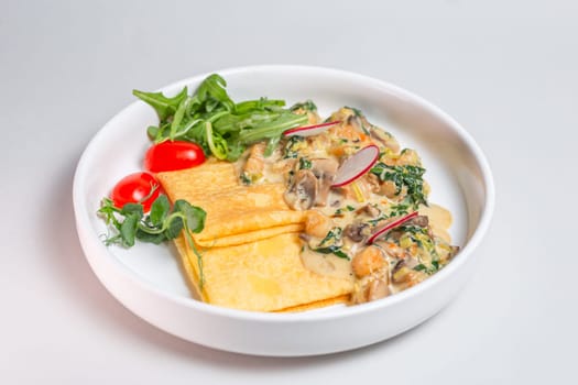 Savory crepe with creamy mushroom sauce, fresh greens on a white plate. Perfect for a light and satisfying meal.