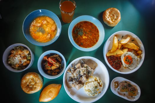 A variety of delicious and healthy food displayed on a green table. The spread features soups, salads, bread, and refreshing drinks.