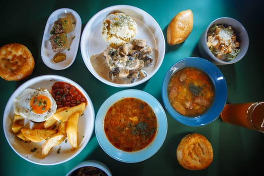 Top view of a table full of delicious traditional russian food with beer and bread. There are 6 different plates on the table.