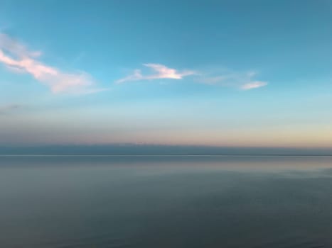 Aerial view of vast lake at dawn with clear blue sky and distant mountains. Ideal for travel sites, backgrounds, and wallpapers.